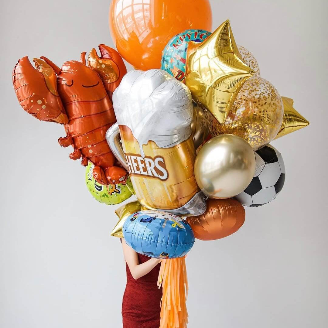 A vibrant collection of character foil balloons, including a lobster, soccer ball, and cheers beer design.