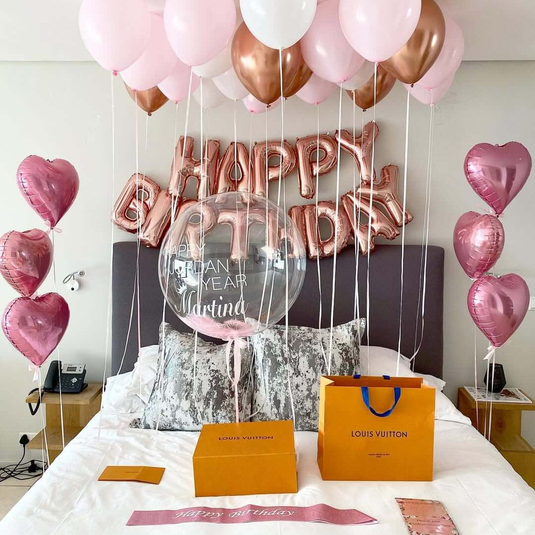 Decorative balloons with 'Happy Birthday 35' on a bed in a room.