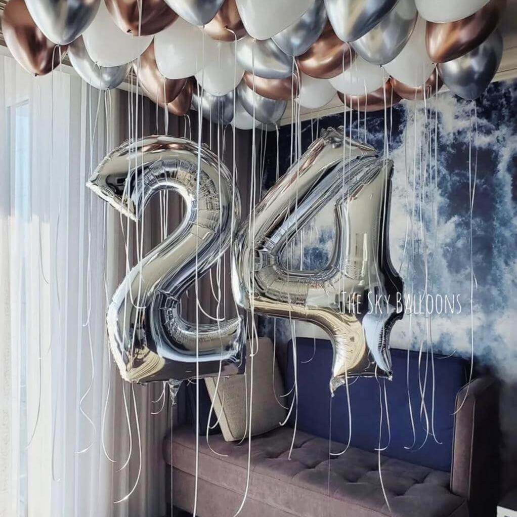 24th birthday celebration balloon setup with metallic silver and chrome balloons covering bedroom ceiling with large number 24 balloons