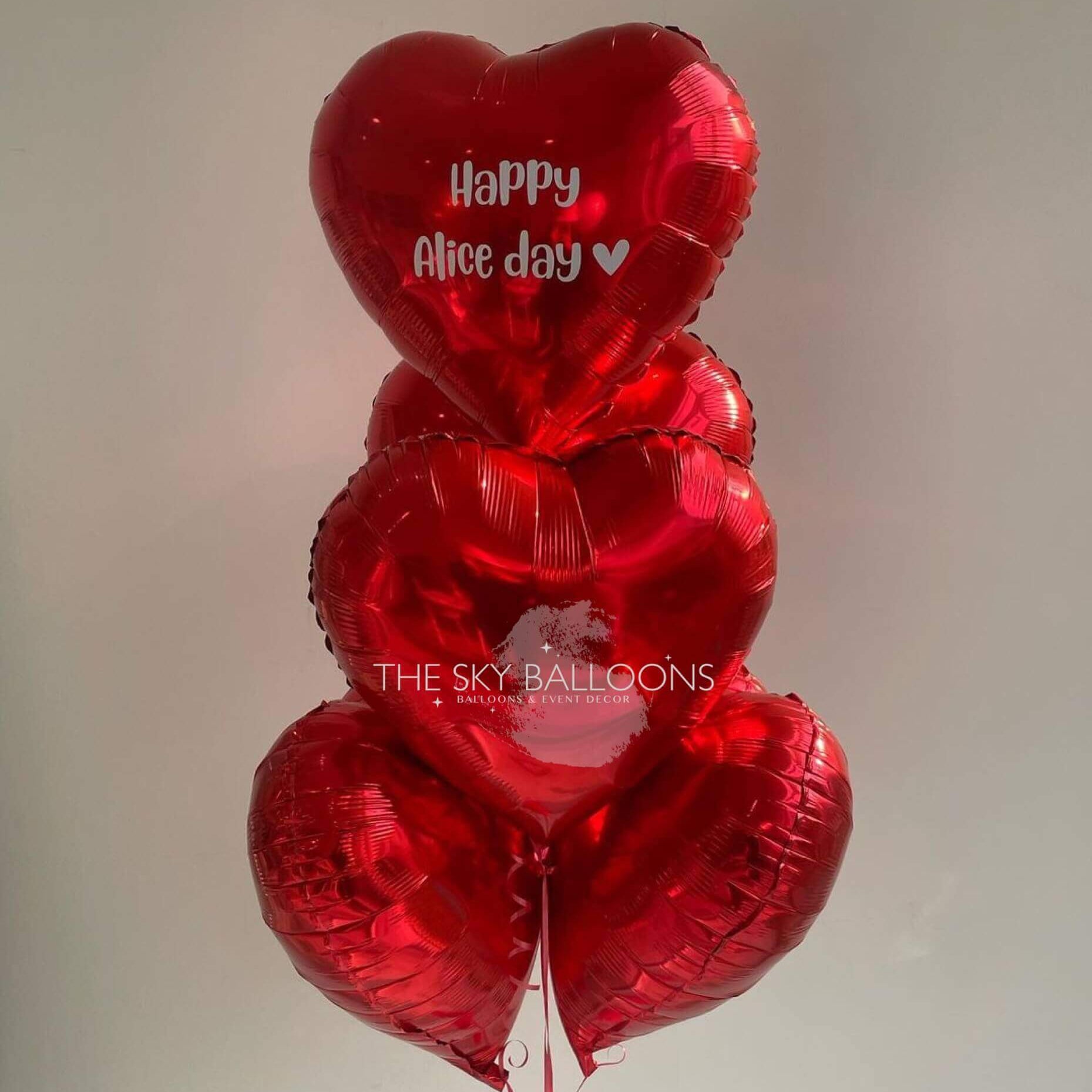 A bunch of red heart-shaped foil balloons with 'Happy Anniversary' written on one of them, tied together.