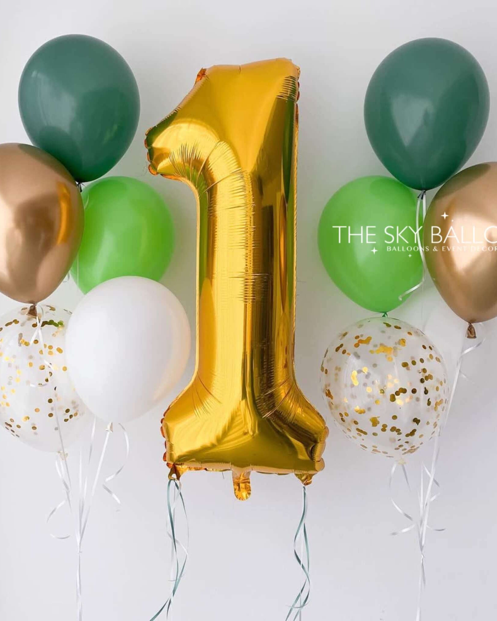 A set of balloons including one large gold number 1 balloon, surrounded by green, white, and rose gold balloons, and two with confetti patterns.