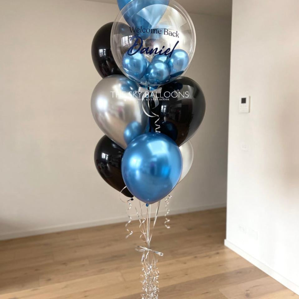 Balloon bouquet with blue, silver, and black balloons in a room.