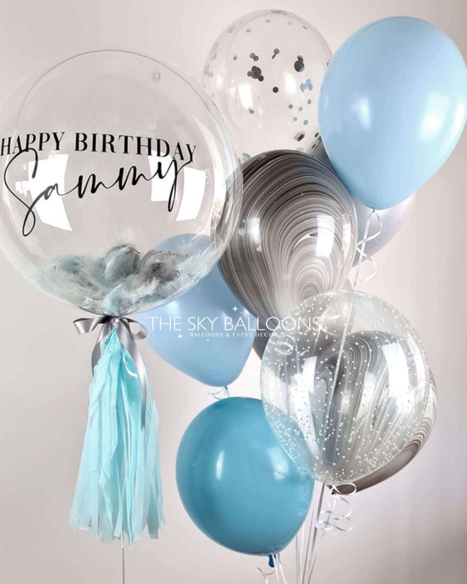 Balloon bouquet with 'Happy Birthday Sammy' on a clear balloon against a light background.