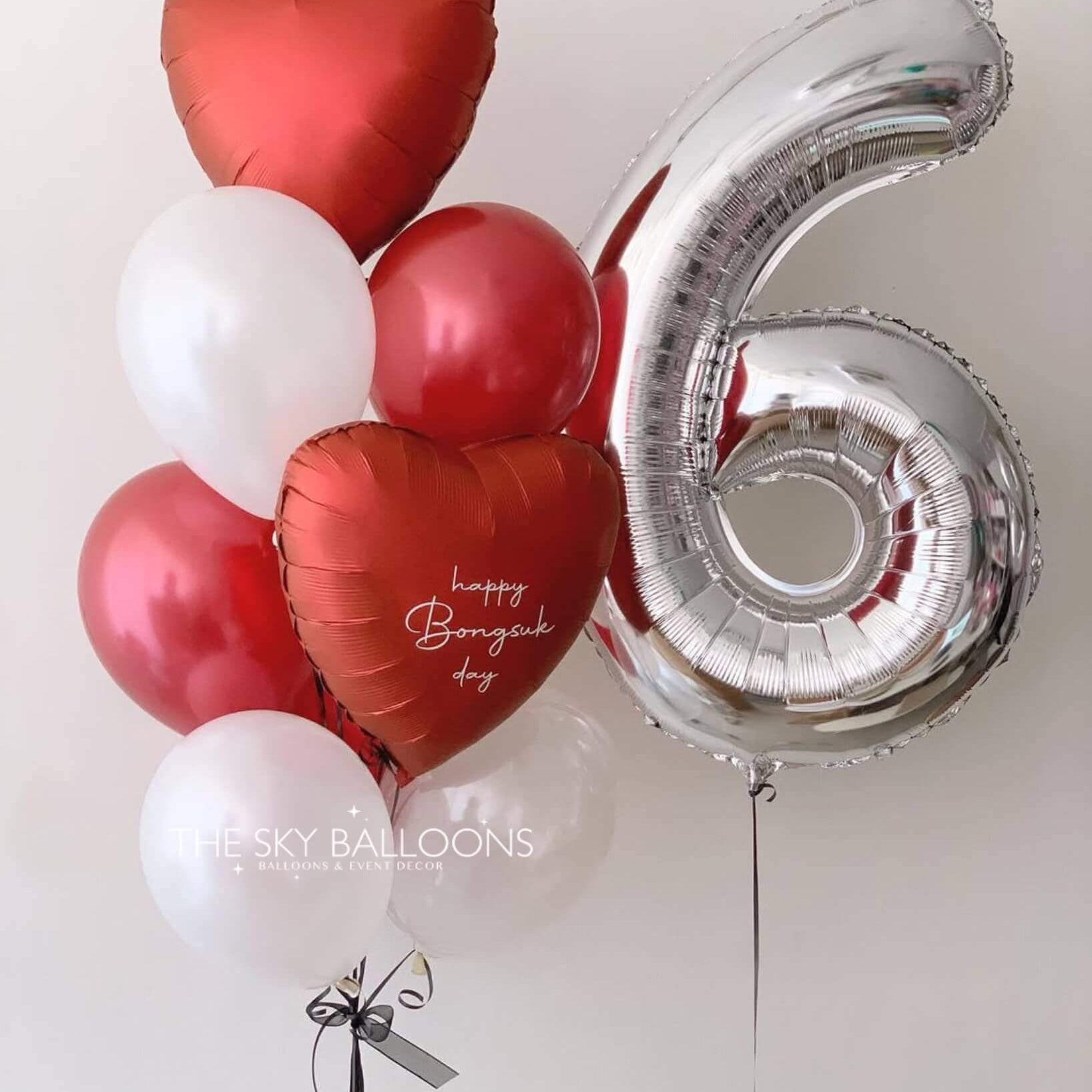 A colorful balloon bouquet featuring a large number six surrounded by red heart-shaped balloons.