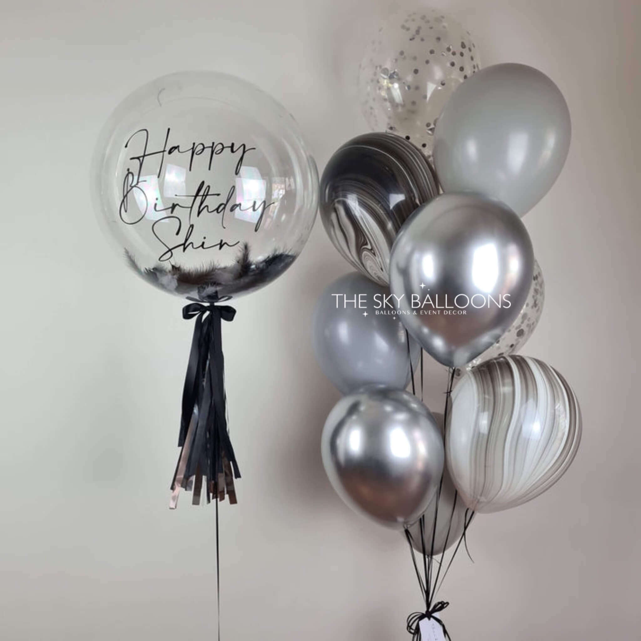 A shiny silver and black balloon with "Happy Birthday" printed on it, adding celebration vibes.