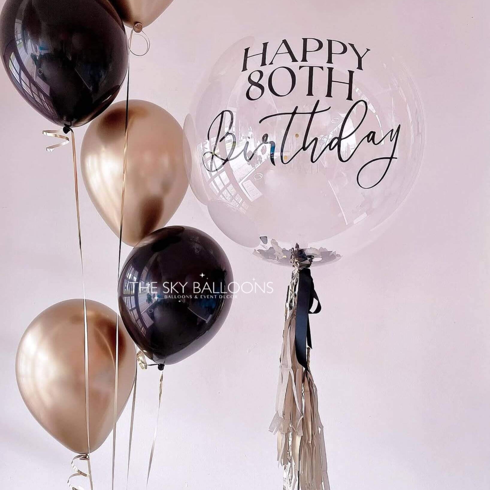 A black and gold birthday balloon with the words "Happy Birthday" printed in elegant lettering