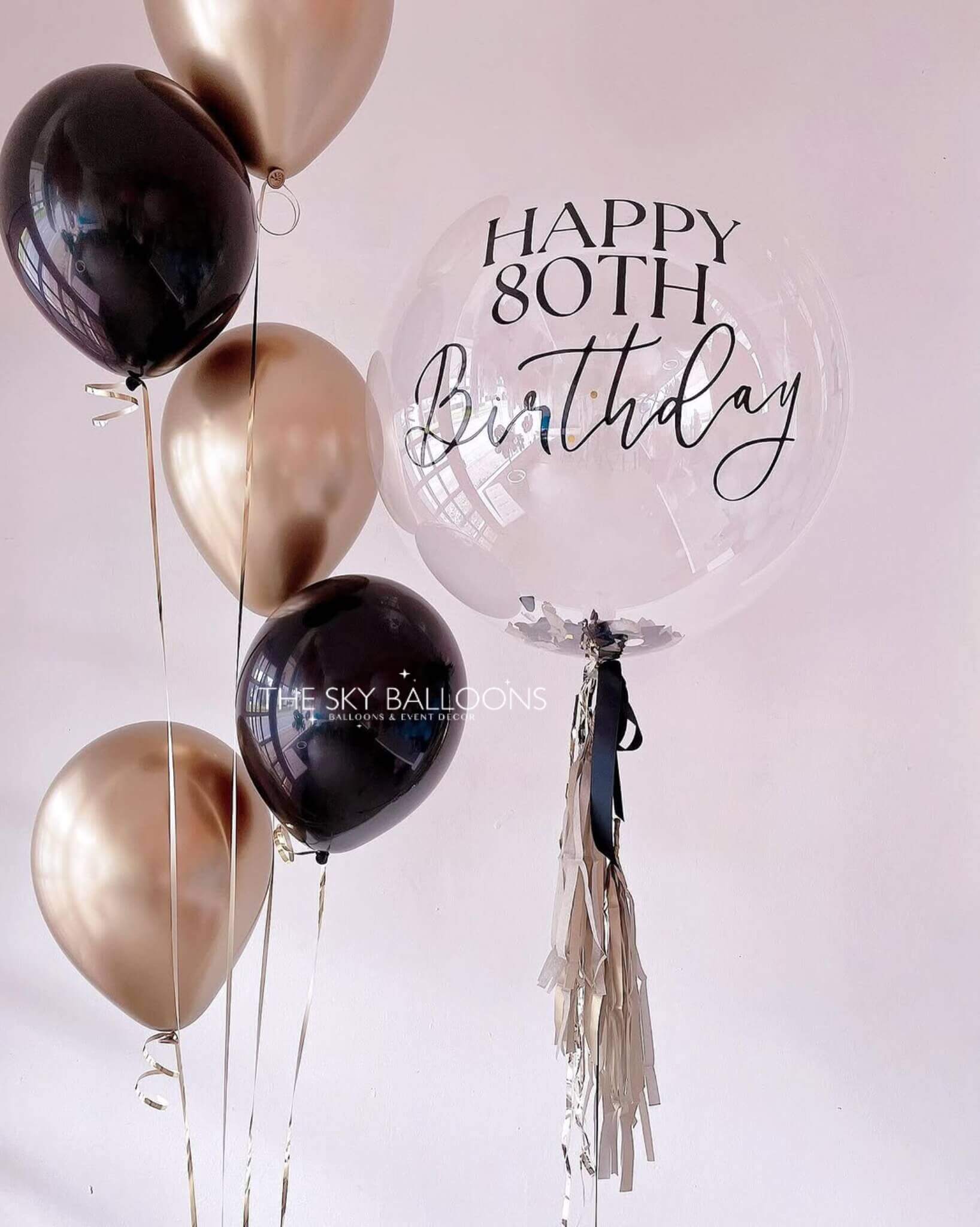 A black and gold birthday balloon with the words "Happy Birthday" printed in elegant lettering