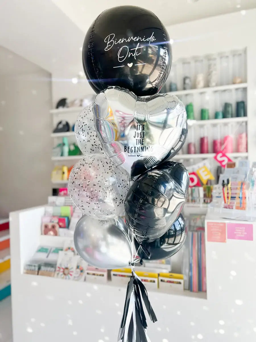 Black and silver balloon bouquet with 'Bienvenido Oct' message and heart-shaped foil balloons in elegant arrangement