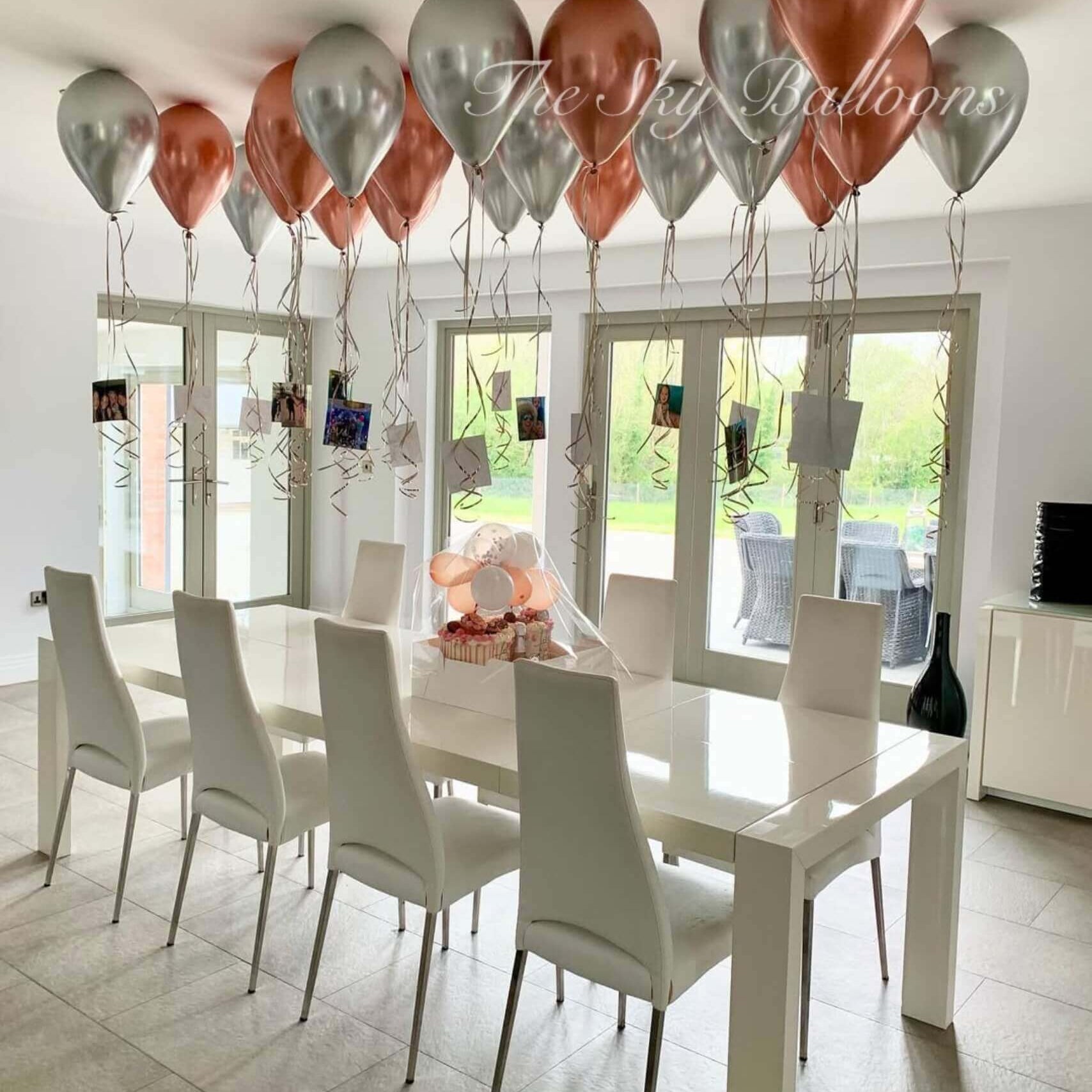 Dining room with a white table and chairs, balloons, and a view of the outdoors.