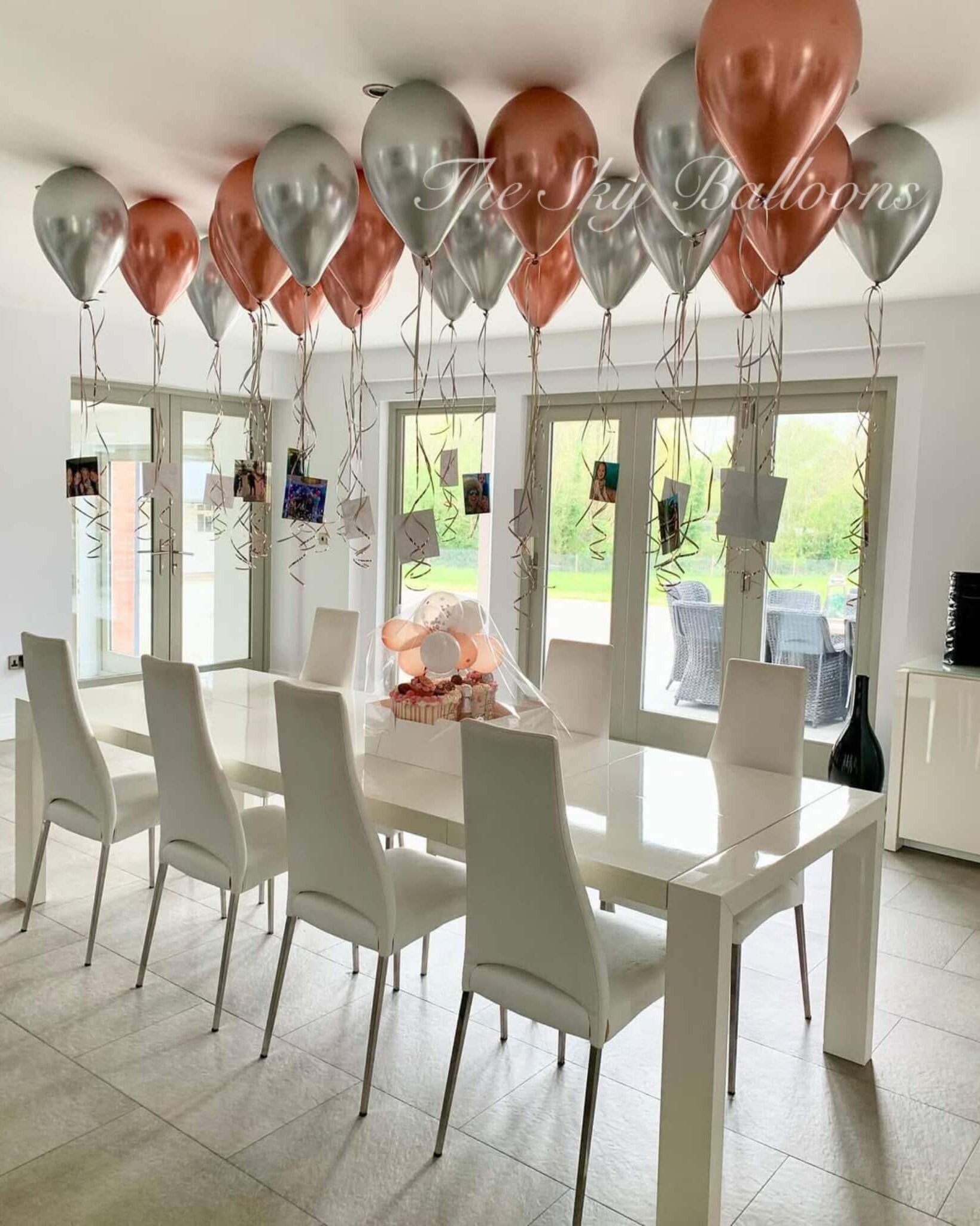 Dining room with a white table and chairs, balloons, and a view of the outdoors.