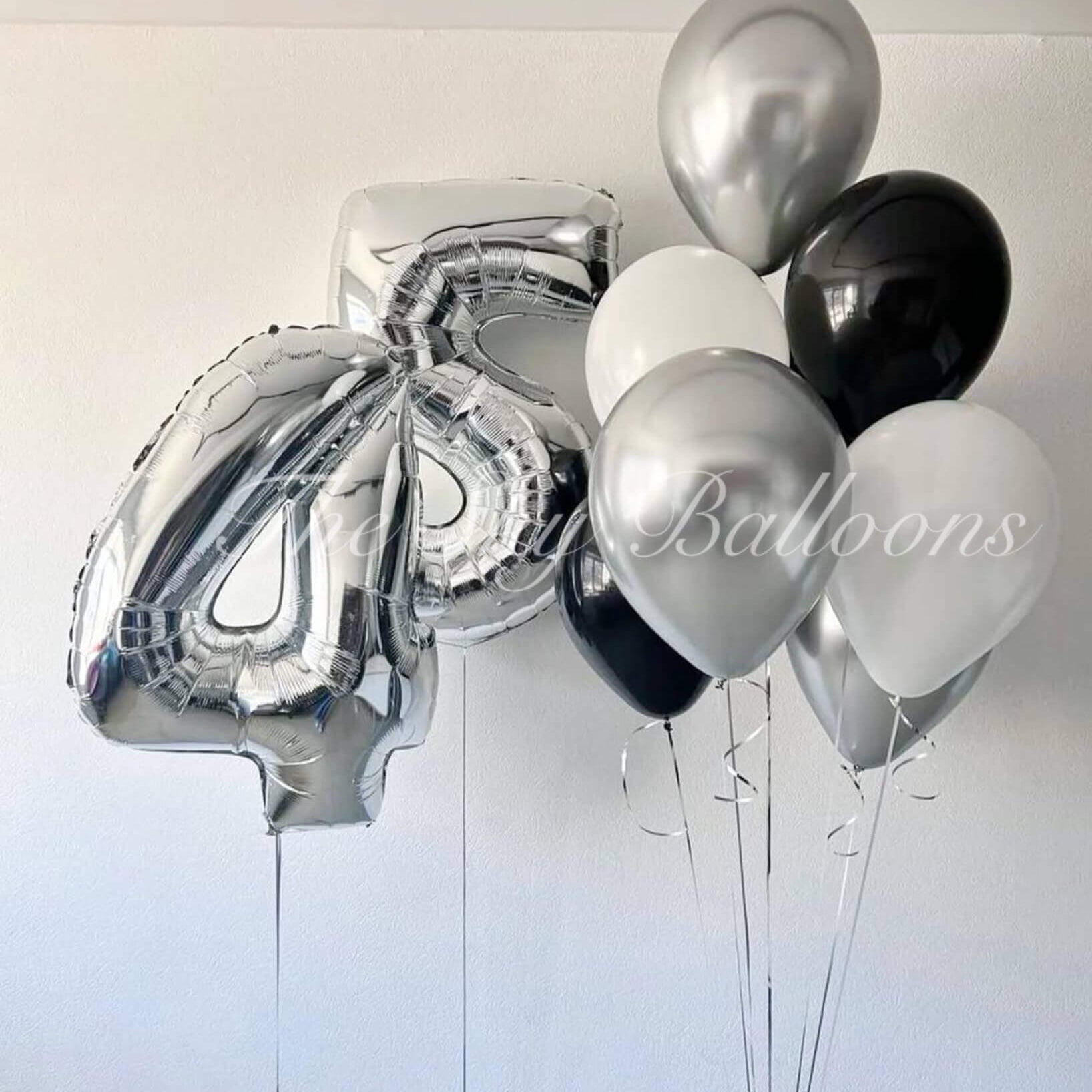 Bunch of silver, black, and white balloons against a white background