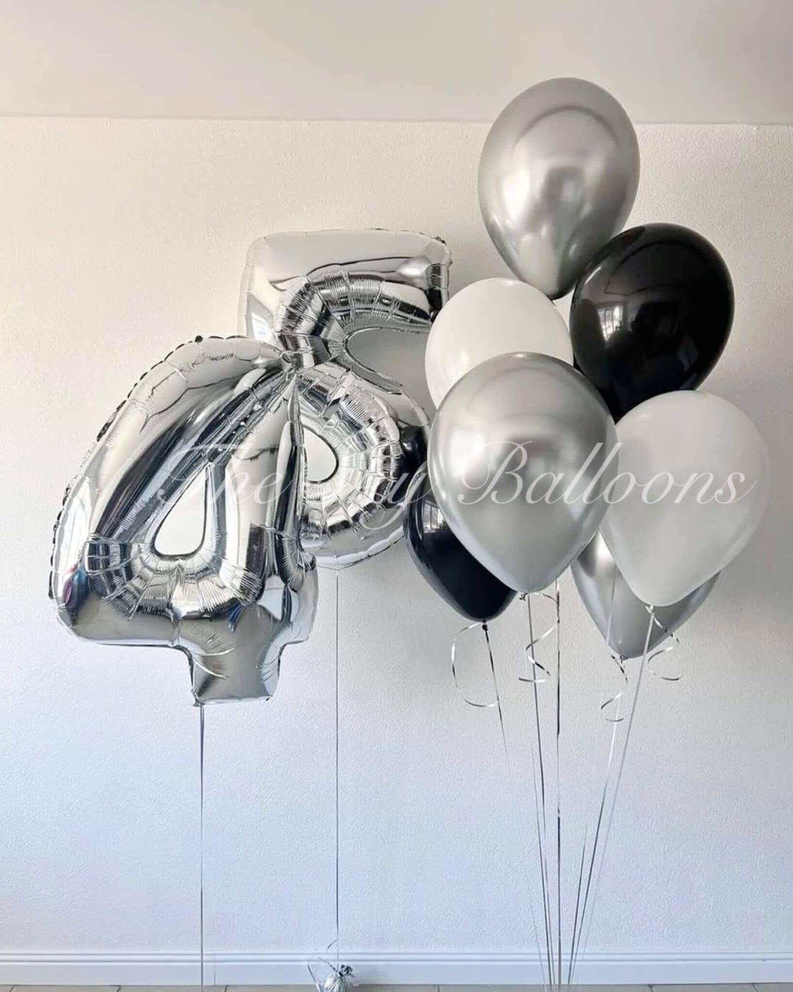 Bunch of silver, black, and white balloons against a white background