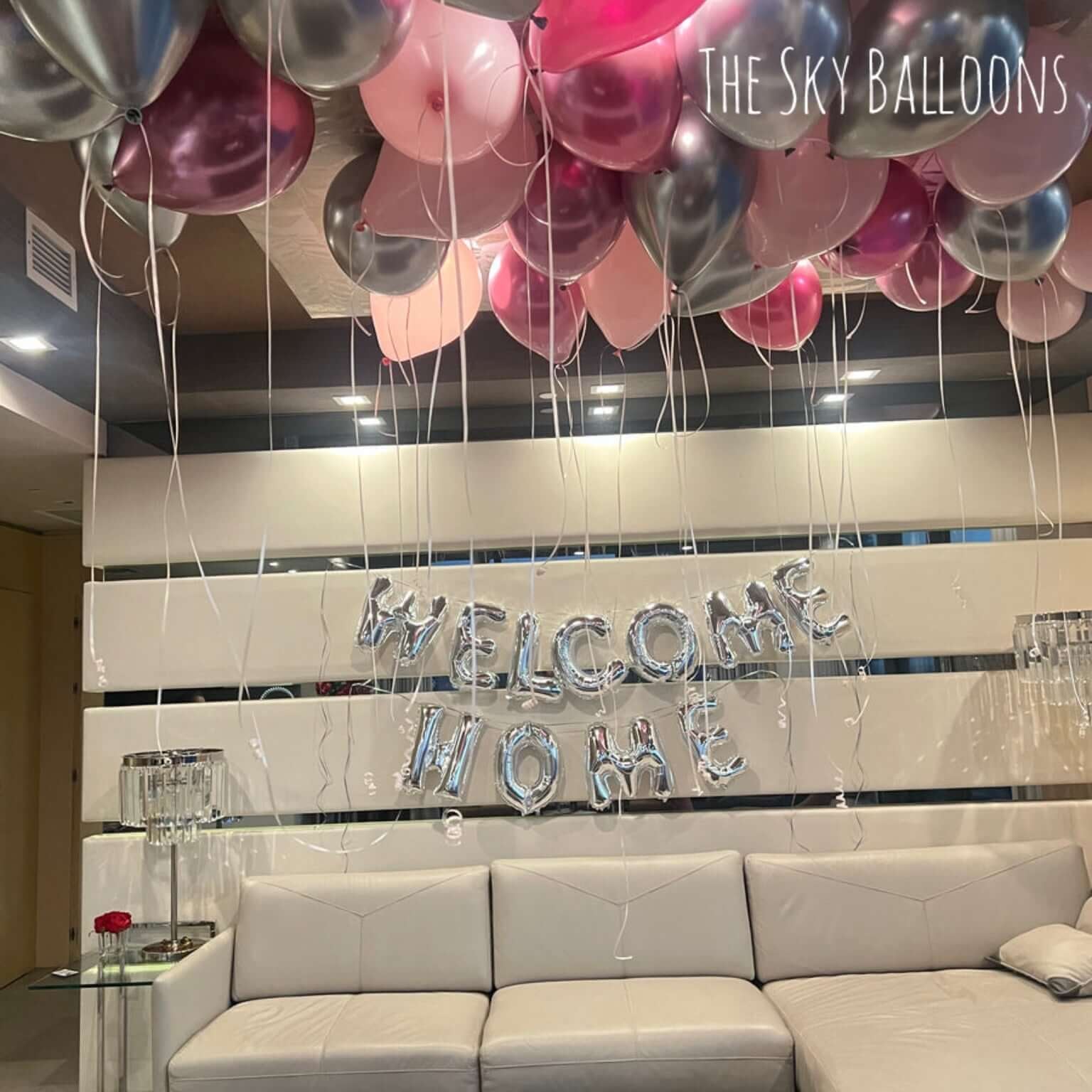 Decorative balloons and 'Welcome Home' sign in a living room setting.