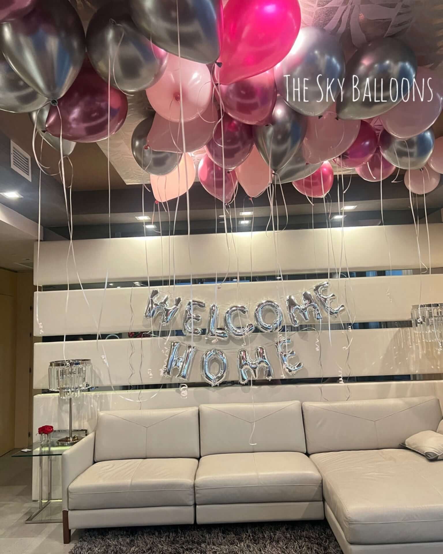 Decorative balloons and 'Welcome Home' sign in a living room setting.