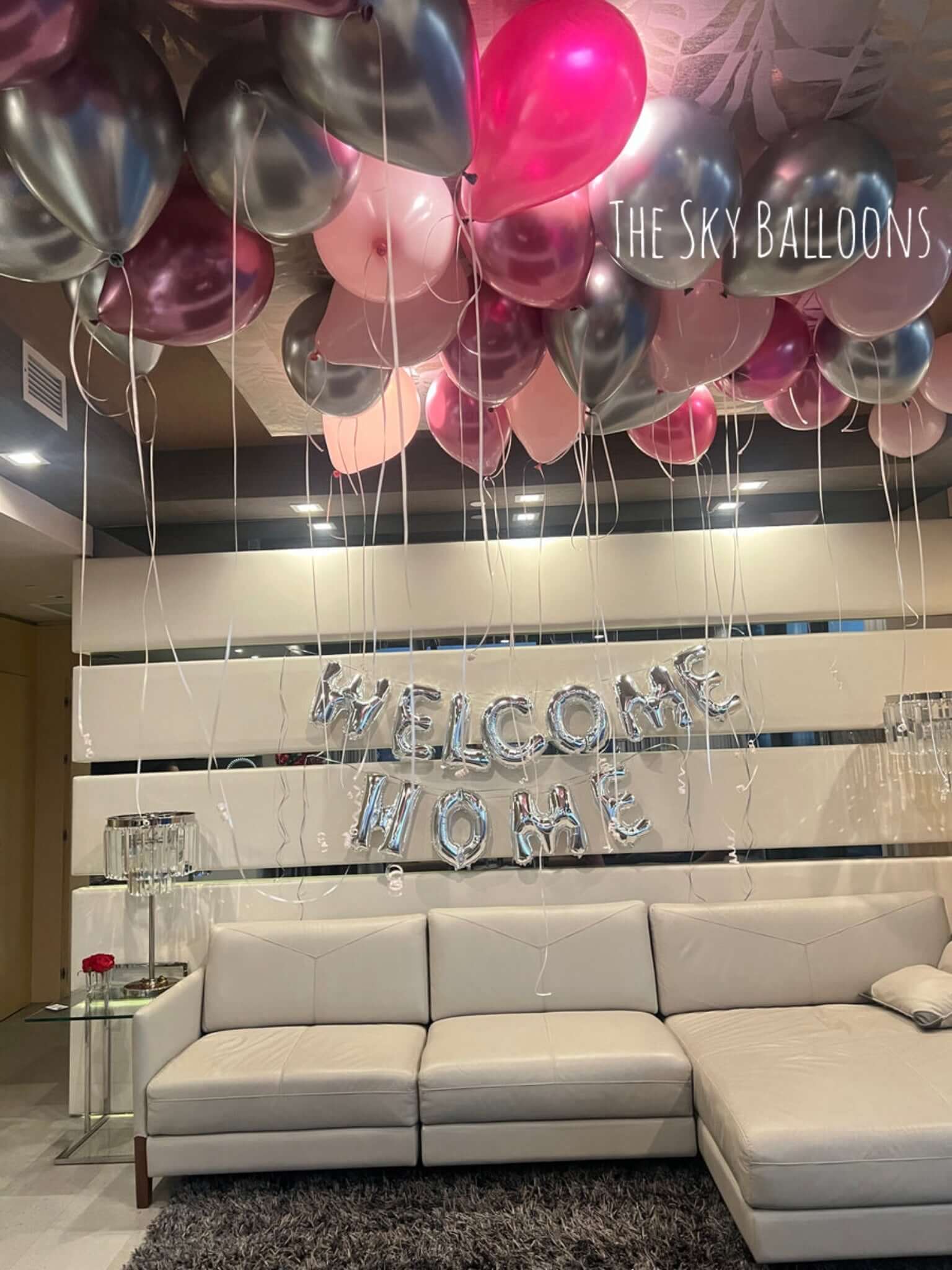 Decorative balloons and 'Welcome Home' sign in a living room setting.