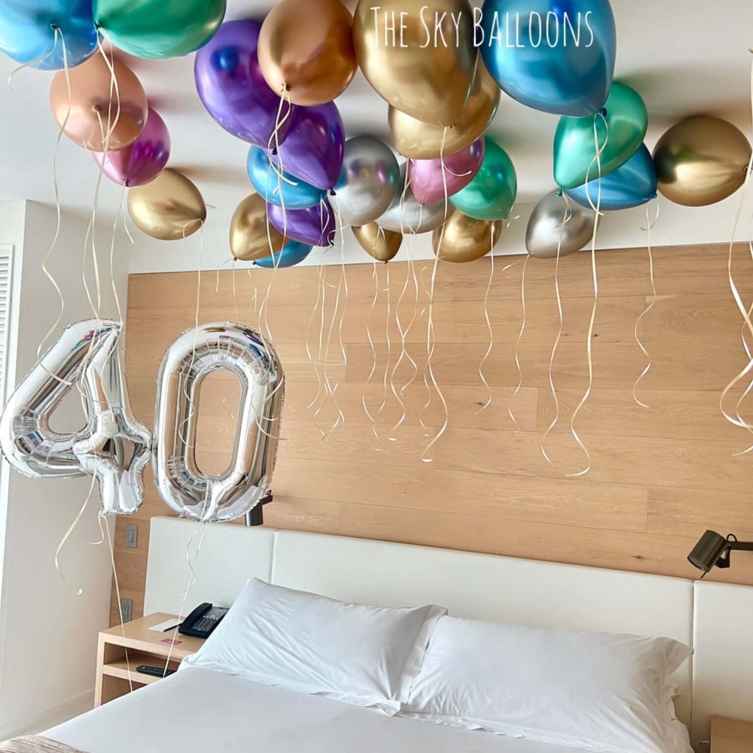 Decorative balloons and a '40' balloon over a bed in a room.