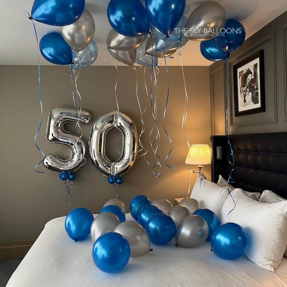 Decorative balloons with '50' on a bed in a bedroom setting.