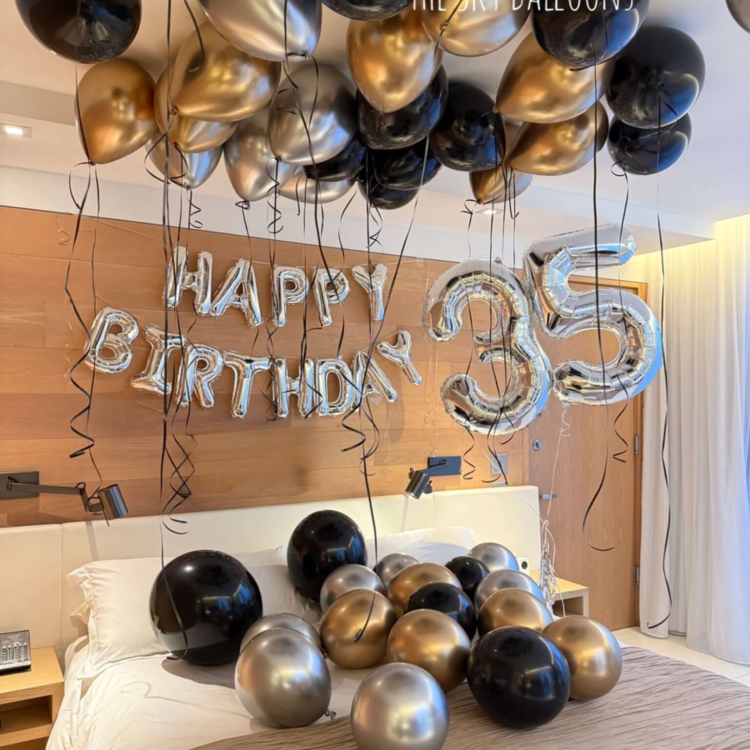 Decorative balloons with 'Happy Birthday 35' on a bed in a room.