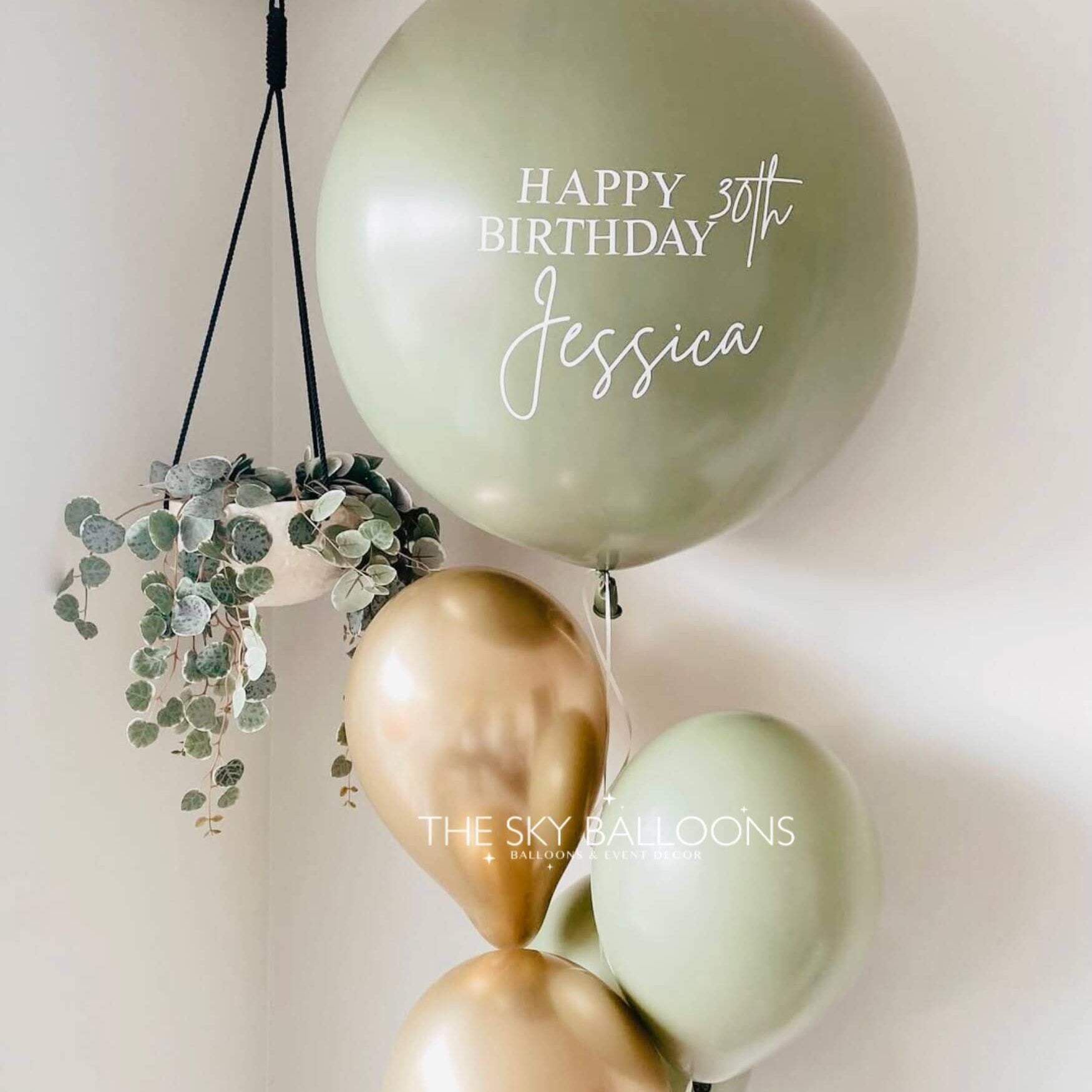 Decorative balloons with 'Happy Birthday Jessica' text and greenery on a light background