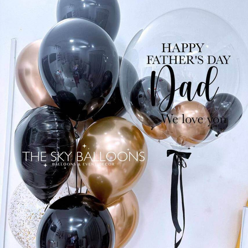 A bouquet of balloons including black and gold colors with 'Happy Father's Day' and 'We love you' text on a balloon, along with other balloons filled with helium gas.