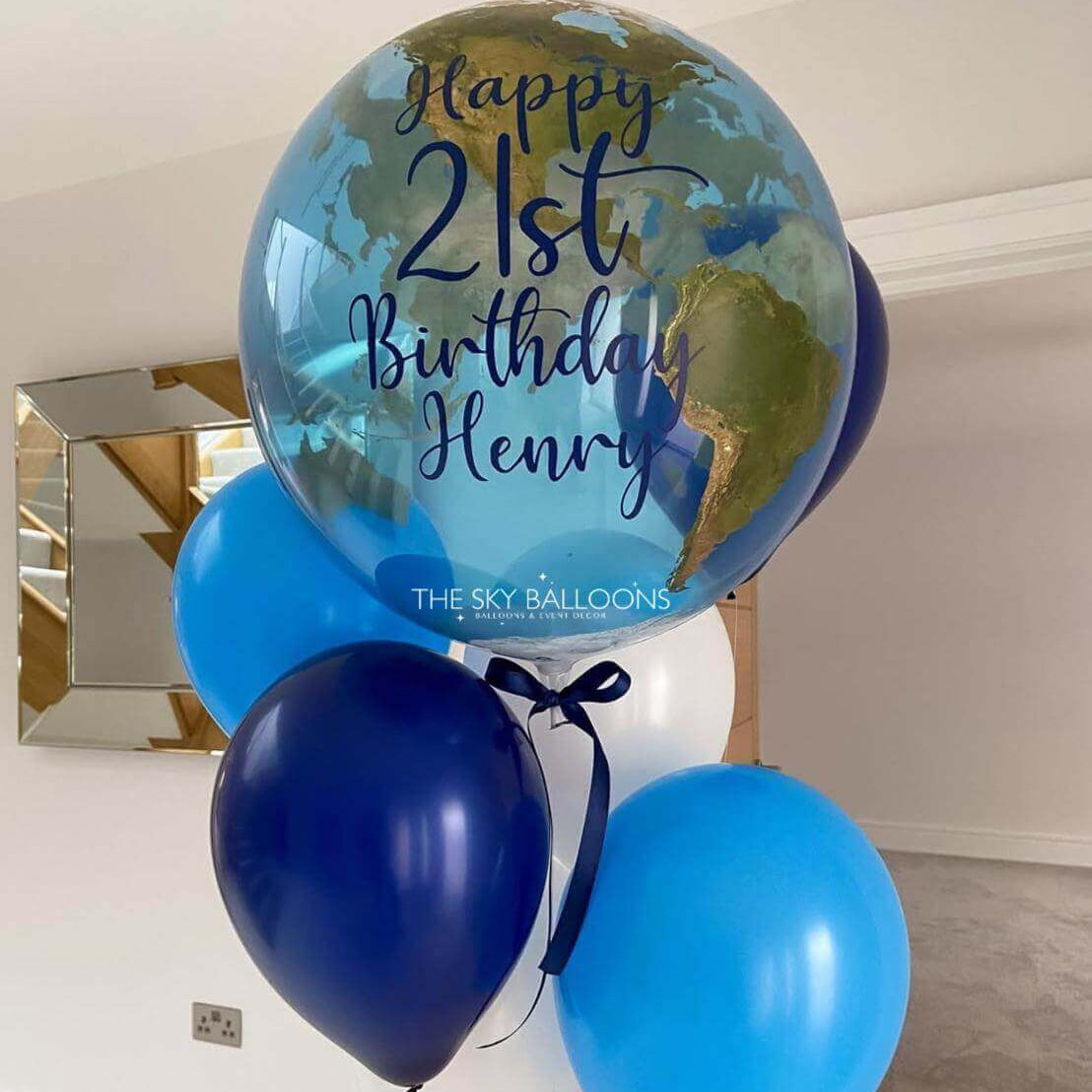 Globular balloon with 'Happy 21st Birthday Henry' text, surrounded by blue and navy balloons, against a neutral background.