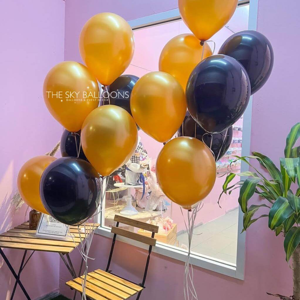 Gold and black balloons with 'The Sky Balloons' branding against a pink wall.
