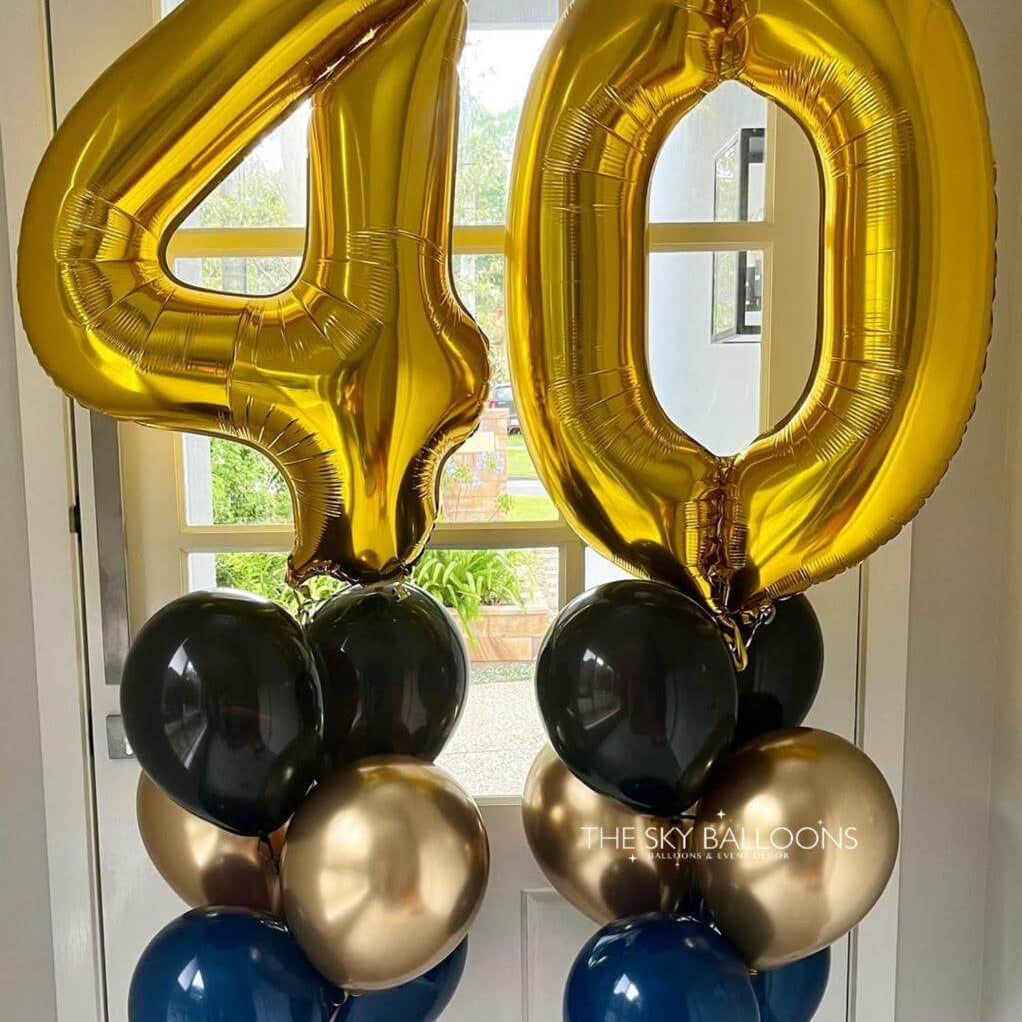 Gold, black, and blue balloons shaped like the number 40 against a white door background.