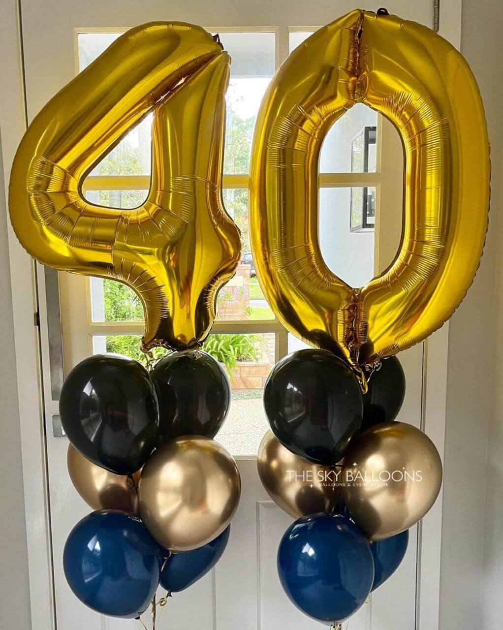 Gold, black, and blue balloons shaped like the number 40 against a white door background.