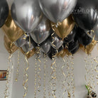 Decorative balloons in black, gold, and silver with ribbons against a neutral background.