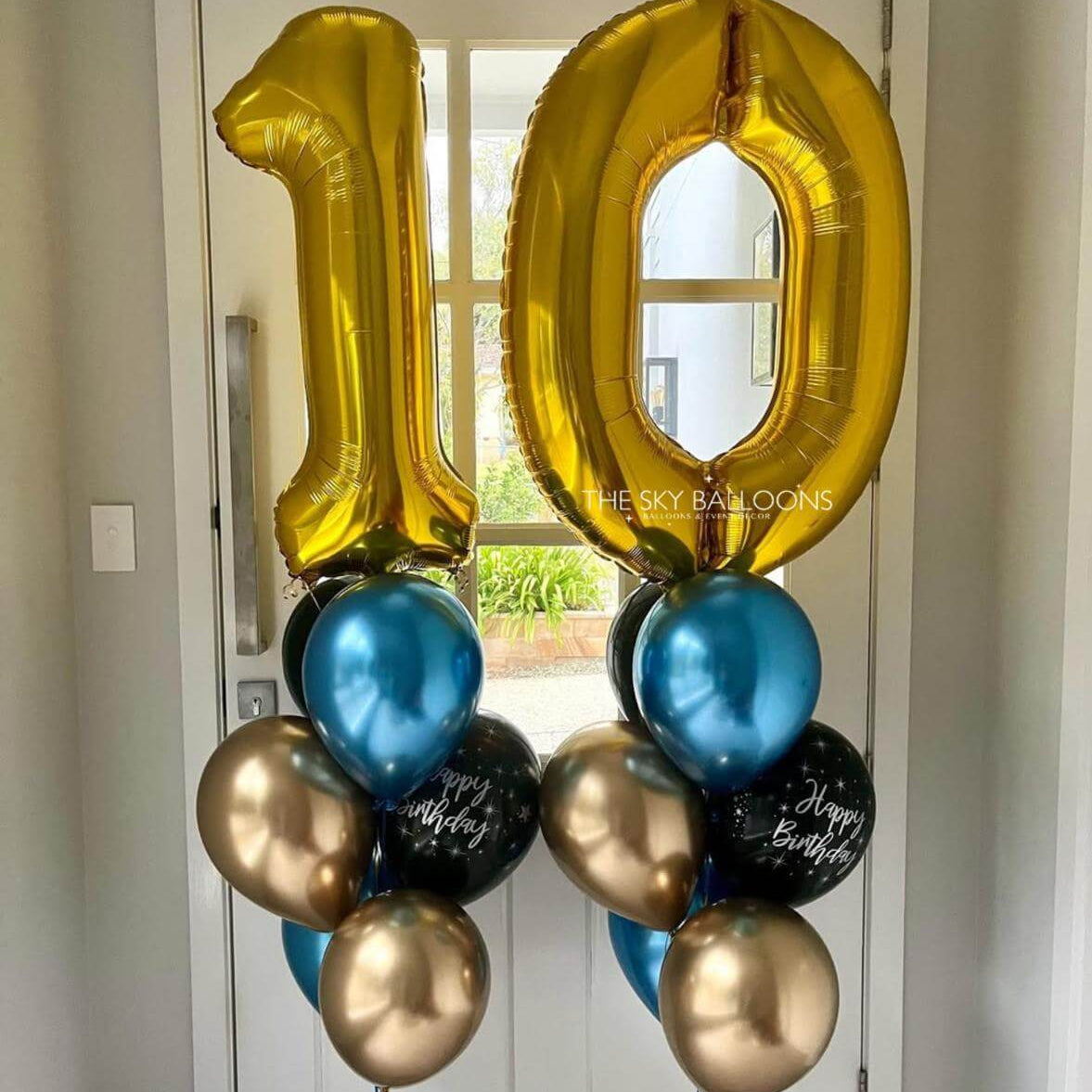 Gold, blue, and black balloons shaped like the number '10' on a door.