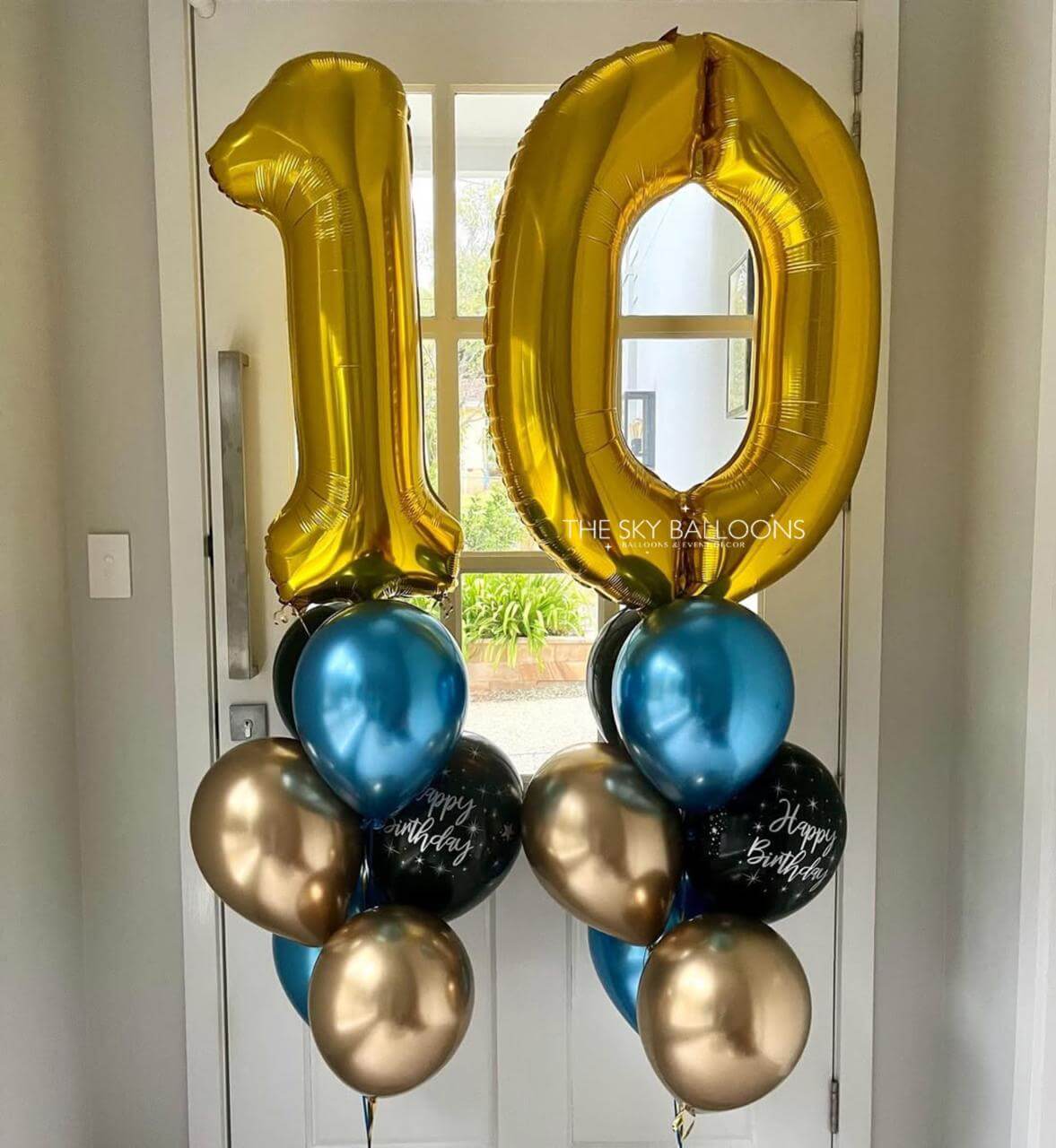 Gold, blue, and black balloons shaped like the number '10' on a door.