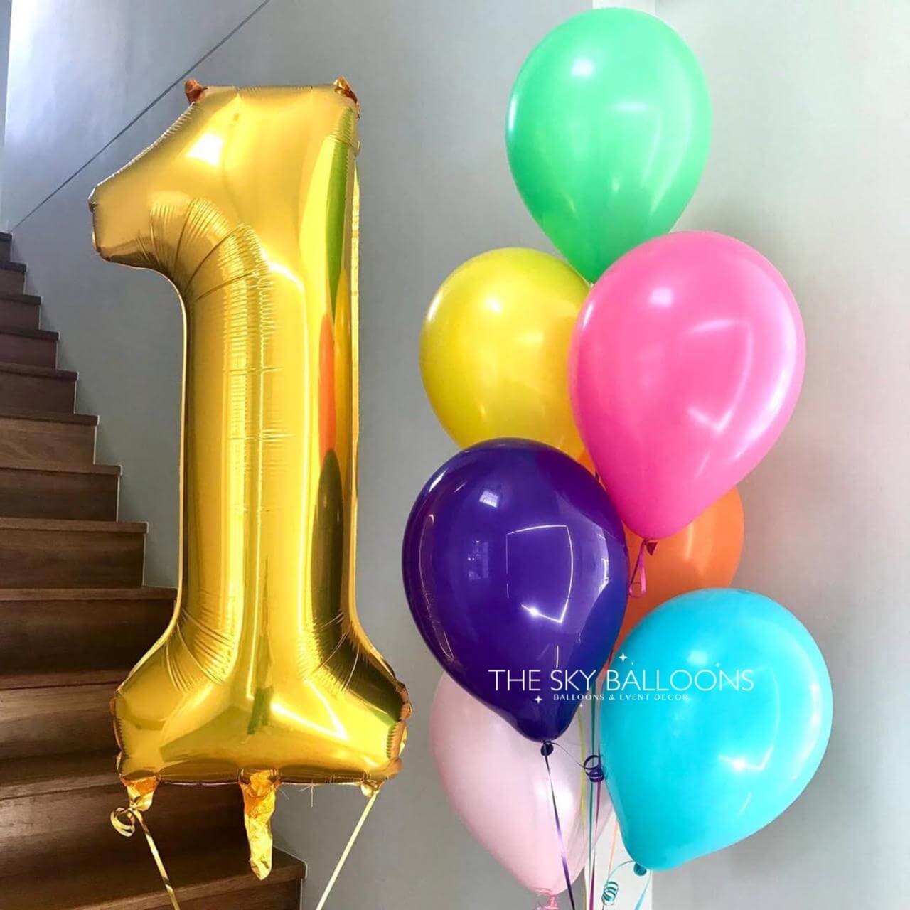 Gold number 1 balloon and colorful bunch of balloons on a staircase.