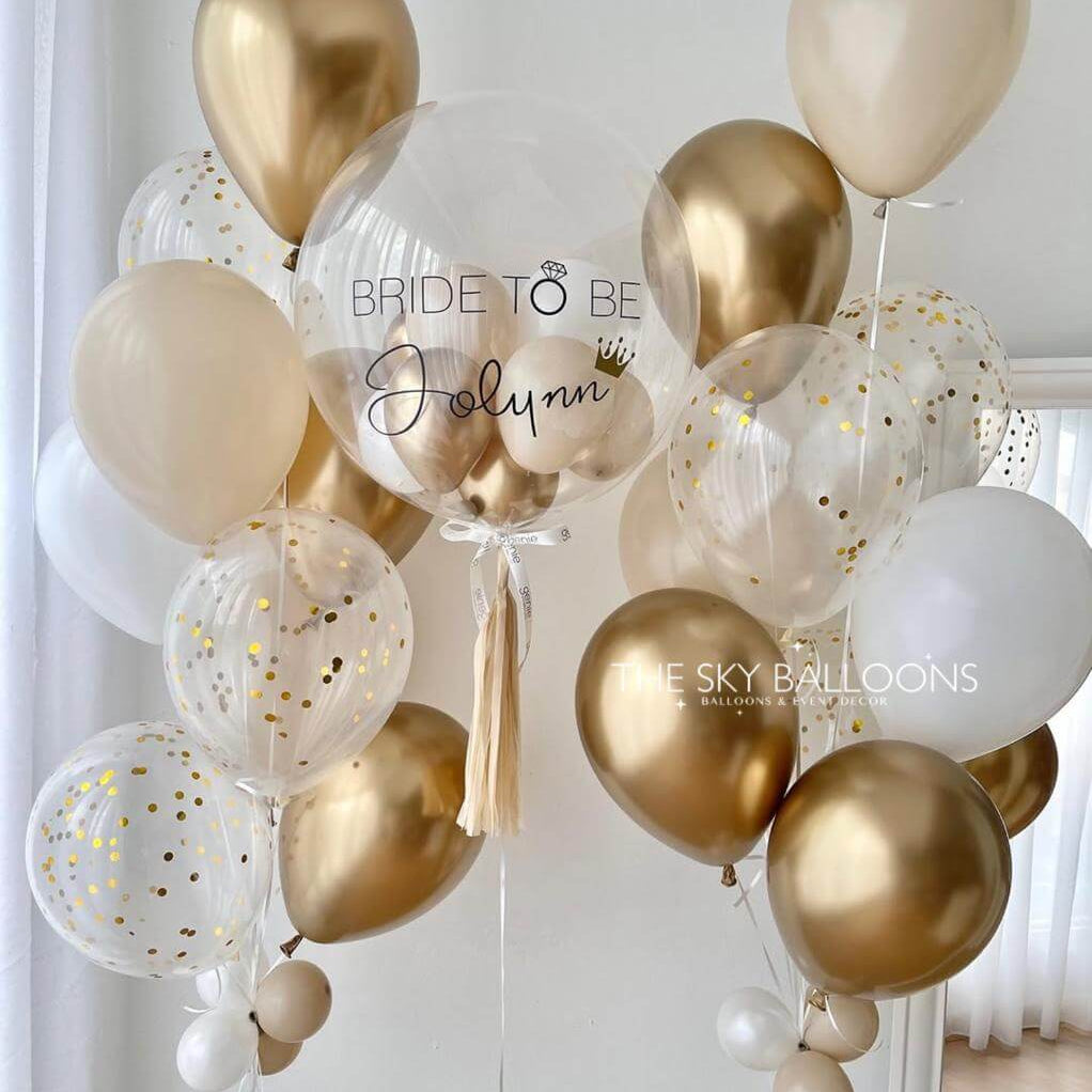 Gold, white, and clear balloons with 'Bride to Be' text against a light background