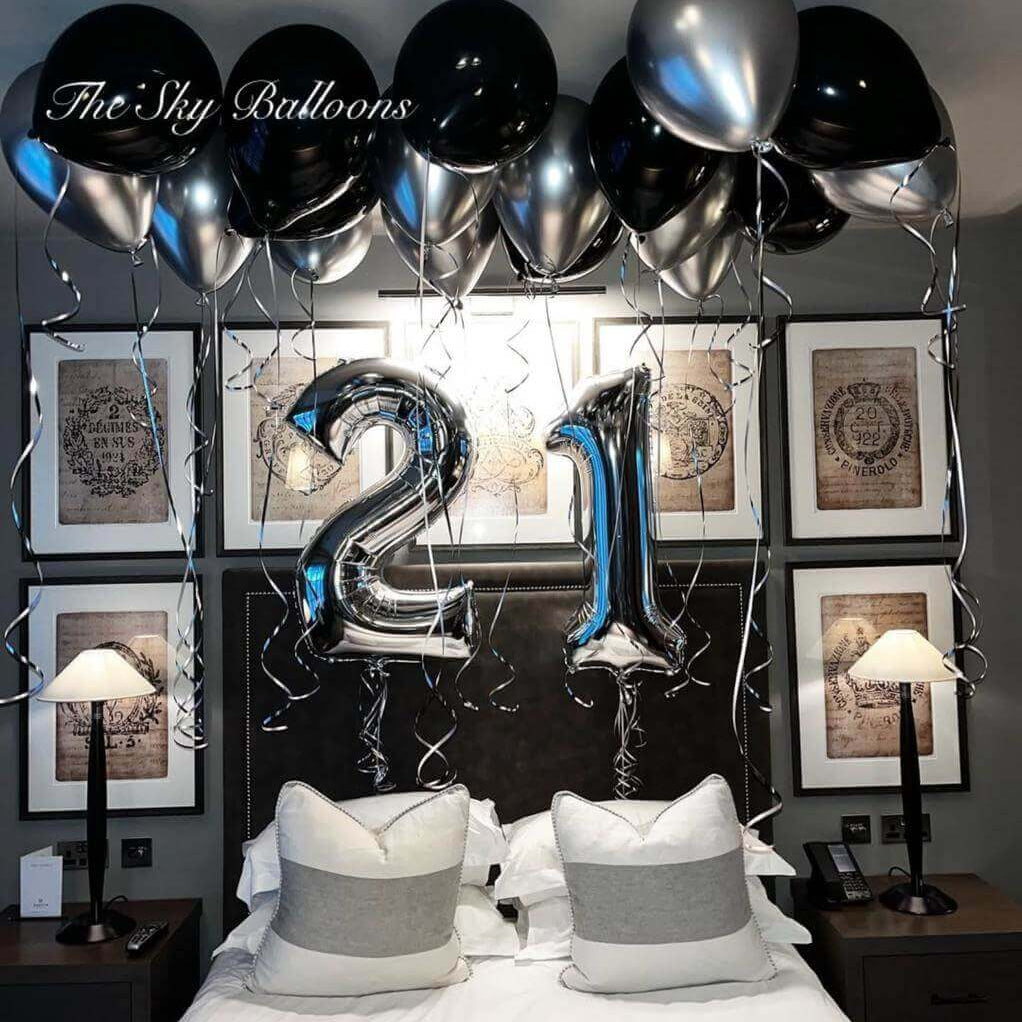 Happy 21st birthday balloon arrangement featuring black and silver balloons in an elegant party setup