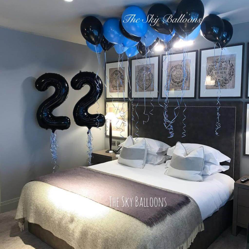 Decorated bedroom with balloons and '22' balloons over a bed.