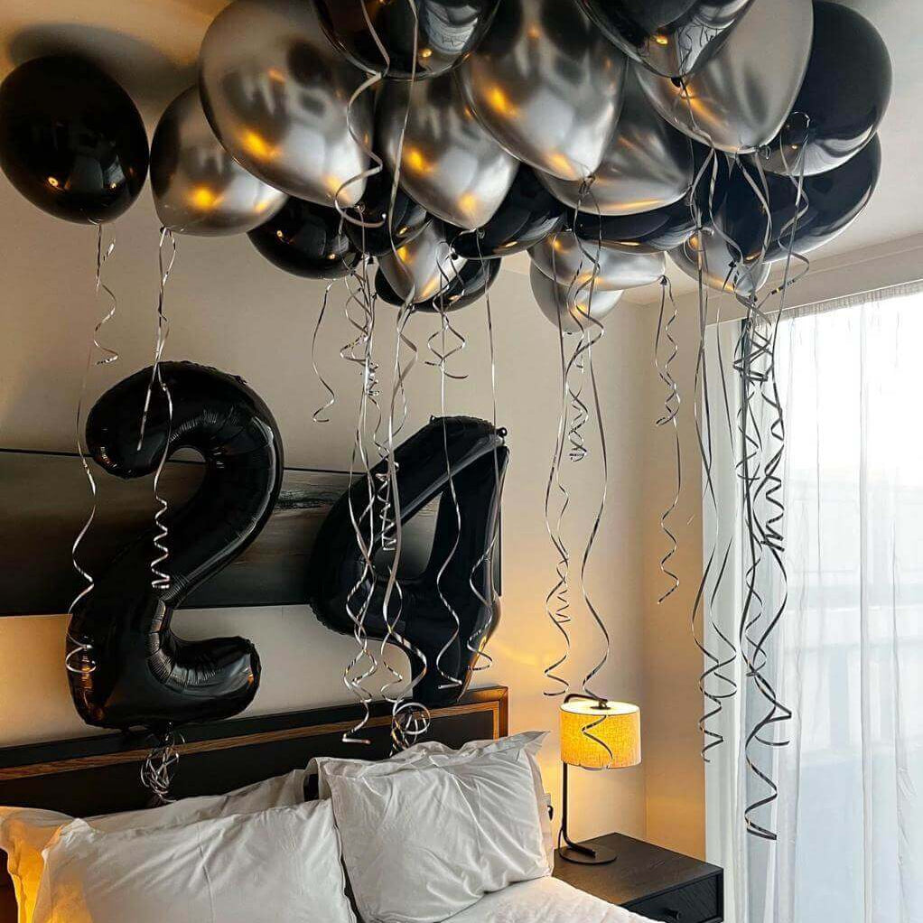 Happy 24th birthday balloon arrangement featuring black and silver balloons in an elegant party setup