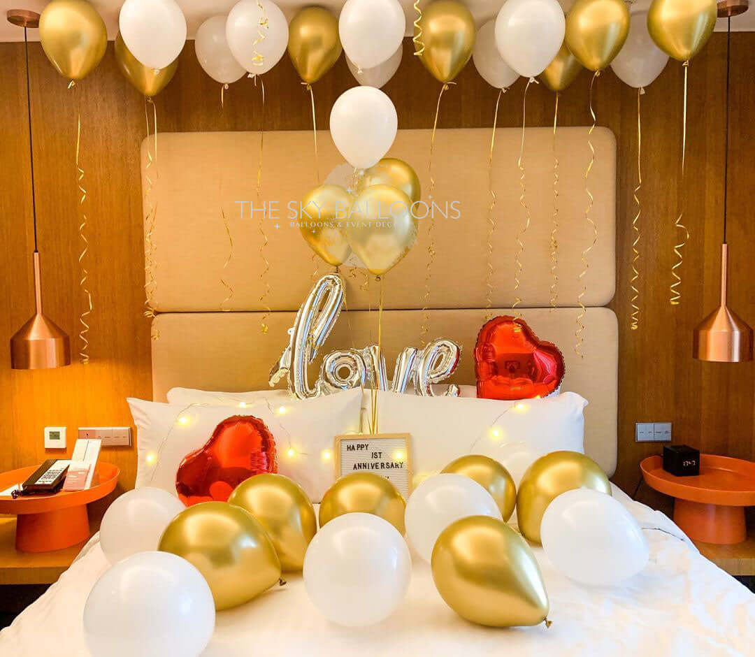 Bed decorated with gold and white balloons, including a heart-shaped balloon.