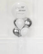 A bunch of balloons with 'Happy Birthday' text on one of the balloons, predominantly in white and silver colors.