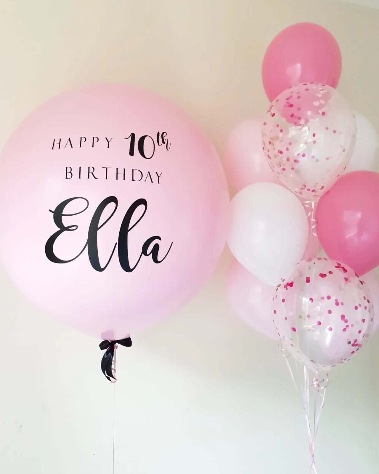 A bouquet of pink and white balloons, with one customized balloon that reads 'Happy 10th Birthday Ella'.