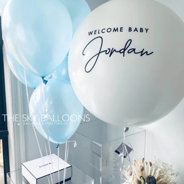 Customized 24-inch helium-filled New Born Baby balloon in pastel blue with smaller decorative balloons, perfect for welcoming a newborn