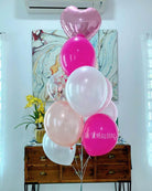 Pink, white, and heart-shaped balloons with 'The Sky Balloons' logo on a wooden cabinet.