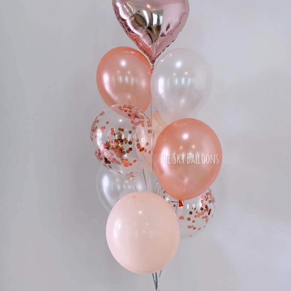 Bouquet of balloons with pink, clear, and heart-shaped balloons on a light gray background.