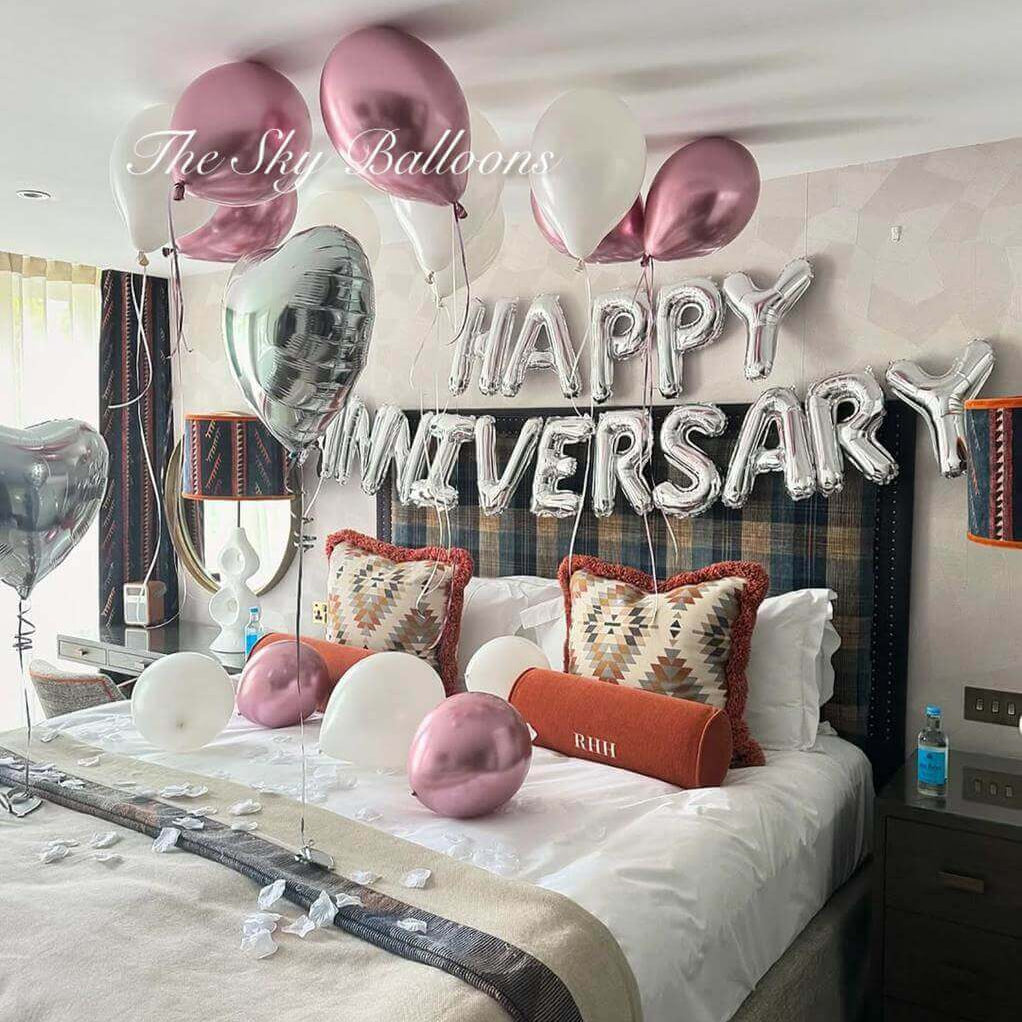 Decorated bedroom with 'Happy Anniversary' balloons and pillows.