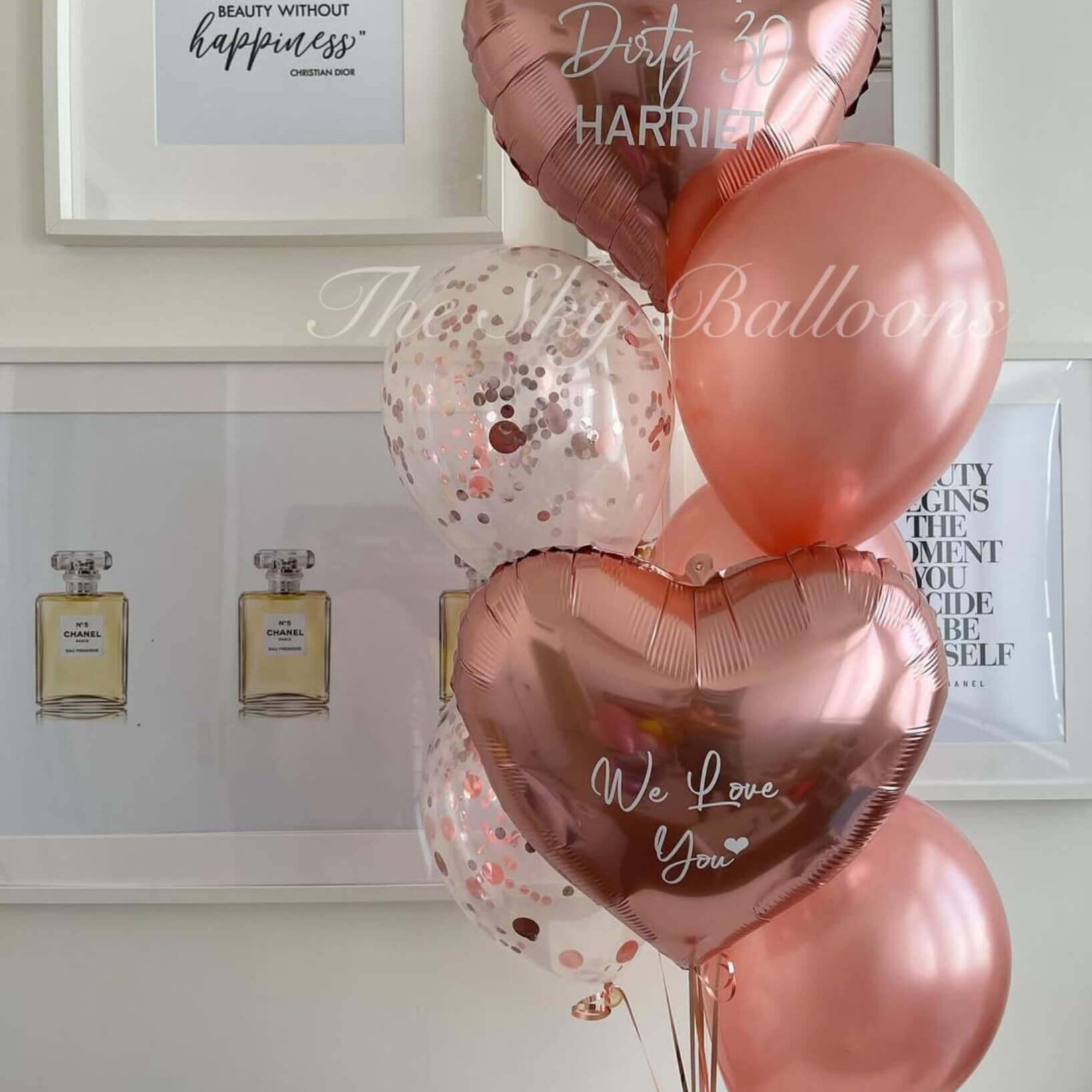Rose gold balloons with personalized messages in a room setting.