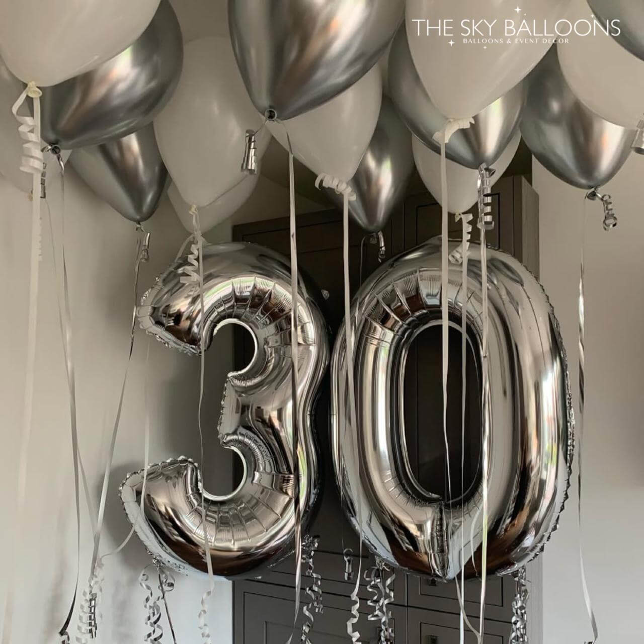 Silver '30' balloons with other balloons against a neutral background