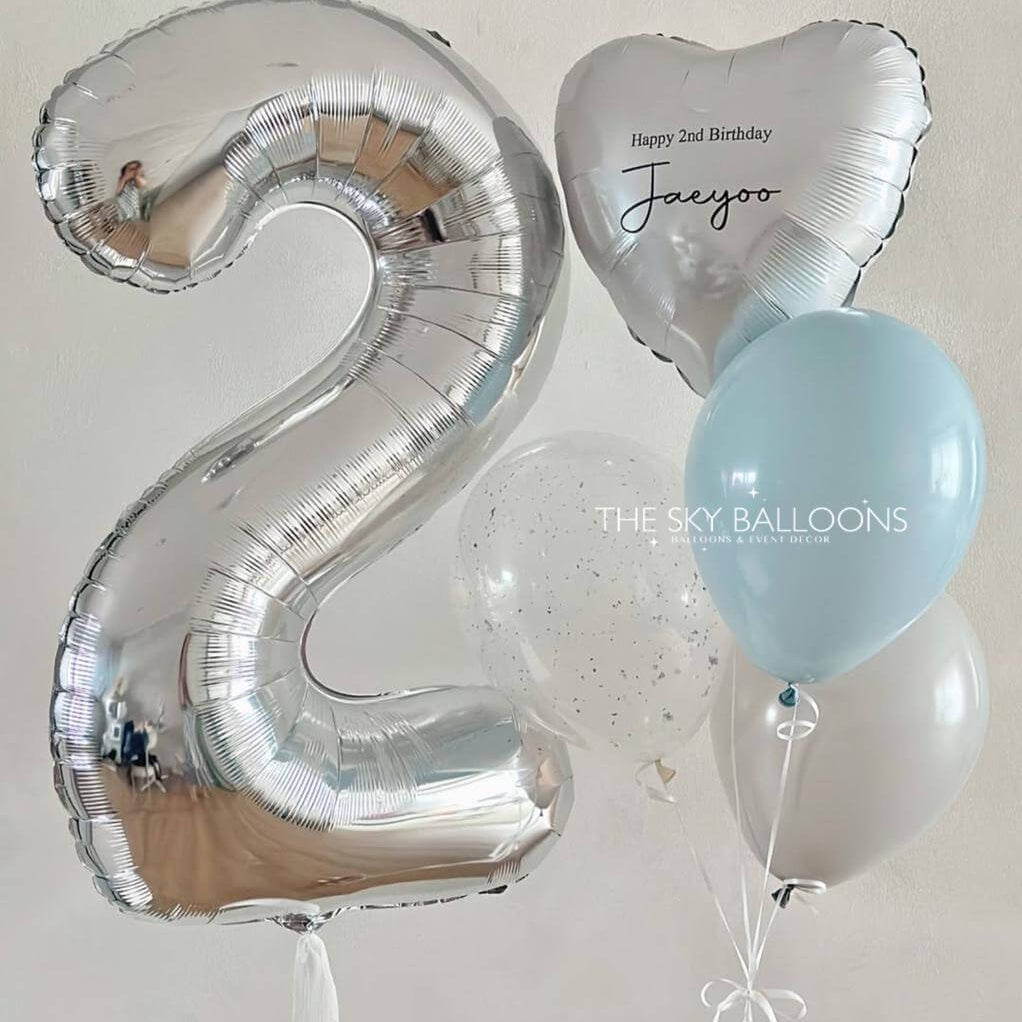 Silver number 2 balloon, heart-shaped balloon with 'Happy 2nd Birthday' text, and light blue balloon on a white background.