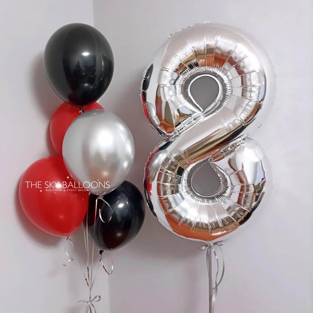 Silver number 8 balloon and other balloons against a white background