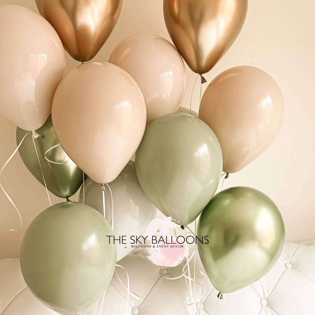 A bouquet of balloons including shades of green, gold, and pink.