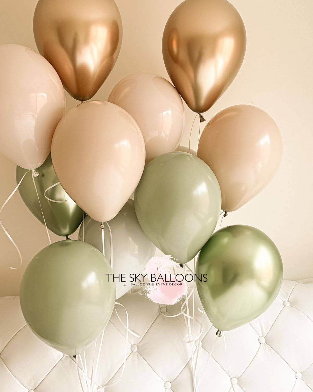 A bouquet of balloons including shades of green, gold, and pink.