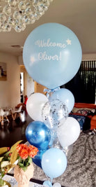 Decorative balloon arrangement with 'Welcome Oliver!' text in a room setting.